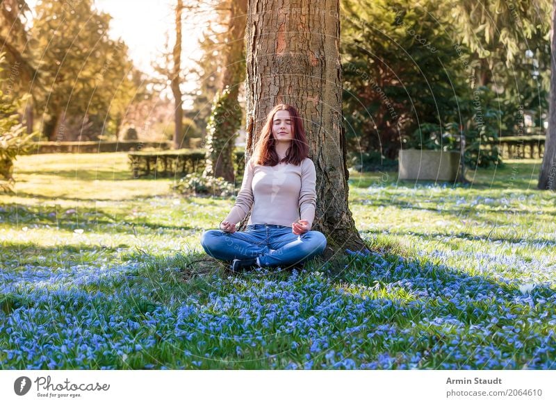 young woman meditates under a tree on a spring meadow Lifestyle Style Joy Happy Healthy Harmonious Well-being Contentment Senses Relaxation Calm Meditation