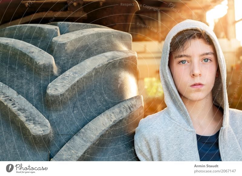 Portrait of a young man leaning against a tracker tire Lifestyle Style already Calm Summer Human being Masculine Young man Youth (Young adults) 1 13 - 18 years