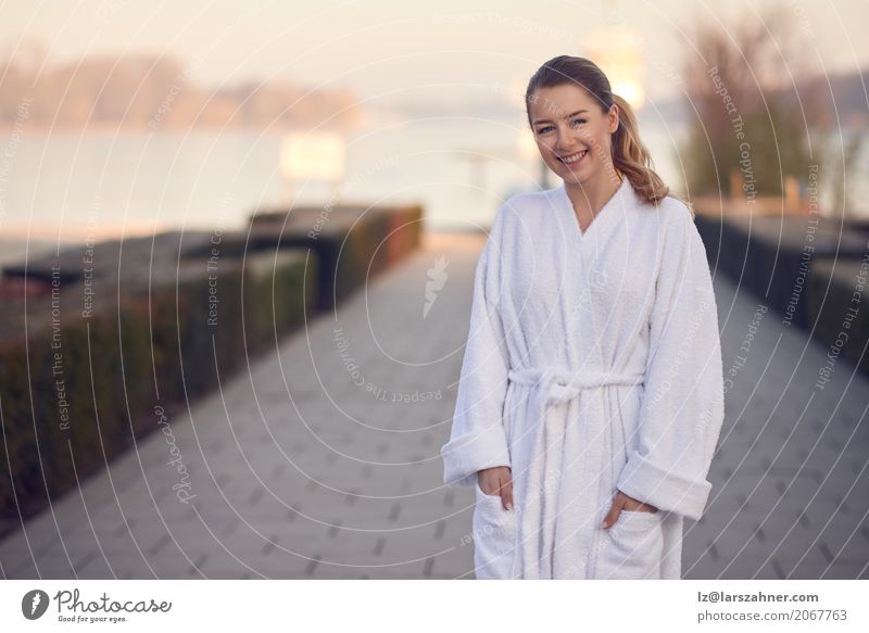 Smiling young woman in a white bathrobe Happy Relaxation Spa Garden Closing time Woman Adults 1 Human being 18 - 30 years Youth (Young adults) Lake Stand