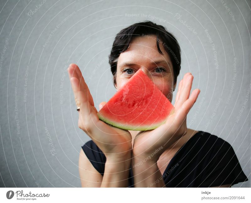 Woman with melon piece in front of her face Fruit Melon Nutrition Organic produce Vegetarian diet Finger food Lifestyle Style Joy Leisure and hobbies Adults