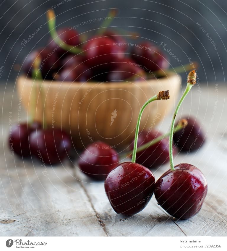 Red cherries in a bowl on a old wooden background Fruit Dessert Nutrition Vegetarian diet Diet Bowl Summer Table Group Dark Fresh Bright Delicious Juicy Berries