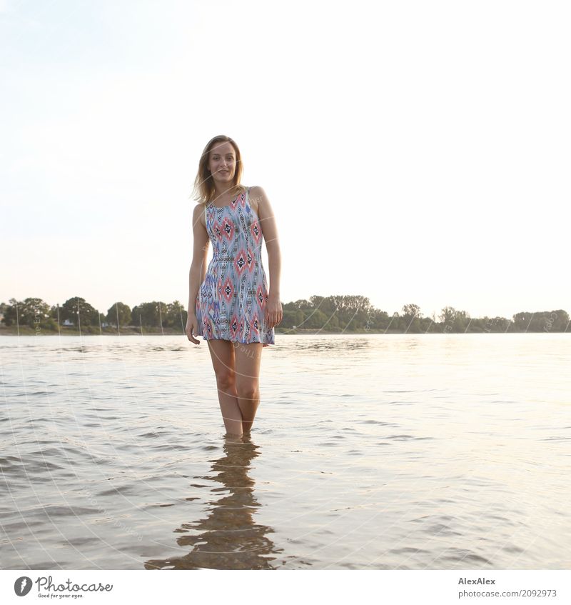 Backlit portrait of a young woman in a summer dress standing with her feet in water Lifestyle Joy pretty Body Well-being Trip Young woman Youth (Young adults)