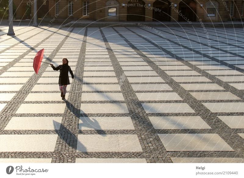Rear view of a woman with a dark coat and umbrella on a large cobbled square in backlight with shadow Human being Feminine Woman Adults 1 45 - 60 years Chemnitz