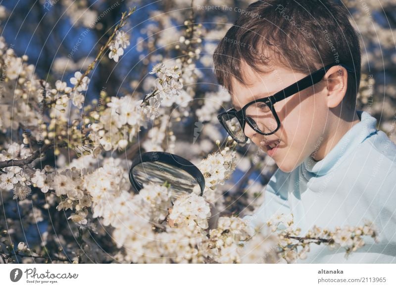 Happy little boy exploring nature with magnifying glass at the day time. Concept of interesting lesson. Lifestyle Joy Face Relaxation Playing Summer Garden