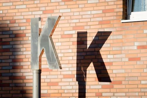 K K Wall (barrier) Wall (building) Characters Town Brown Black Silver Letters (alphabet) Light and shadow Pylon House wall Exterior shot Detail Deserted Day