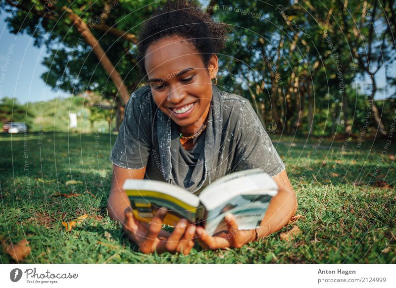 Young woman reading book in the park Youth (Young adults) 1 Human being 18 - 30 years Adults Blossoming Smiling Laughter Study Reading Lie Afro Park Book Grass