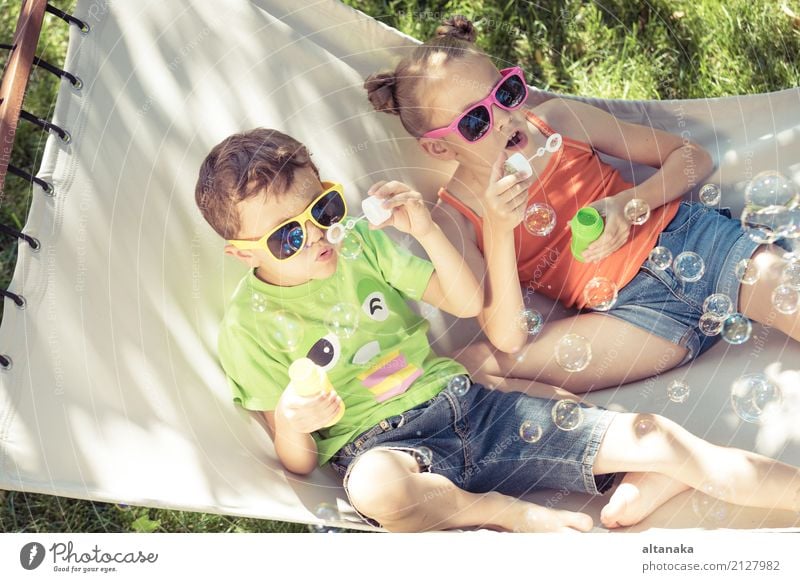 Two happy children lie on a hammock and play with soap bubbles. Lifestyle Joy Happy Beautiful Relaxation Leisure and hobbies Playing Freedom Camping Summer Sun