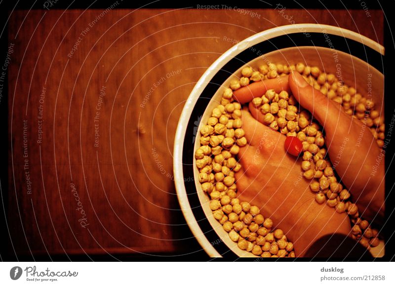 chickpeas Food Nutrition Bowl Skin Hand Fingers Chickpeas Table Wood Emotions Scrabble about Yellow Brown Red Point Colour photo Interior shot Copy Space left