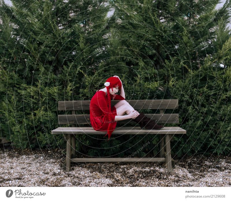 Young woman sitting alone in a wooden bench Human being Feminine Youth (Young adults) 1 18 - 30 years Adults Nature Tree Park Dress Boots Red-haired Wig Braids