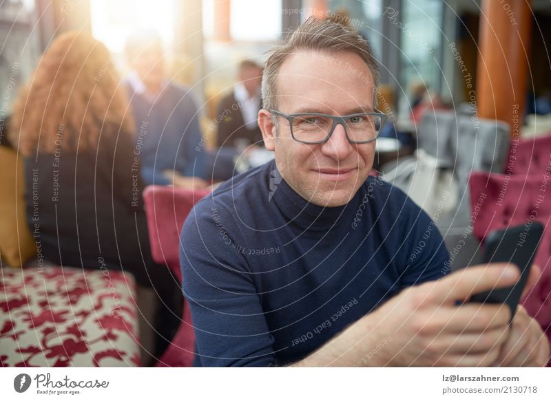Attractive man sitting in a restaurant Restaurant Business Telephone Cellphone PDA Man Adults 1 Human being 30 - 45 years Eyeglasses Smiling Sit Thin attractive