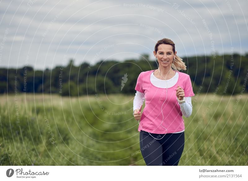 Cheerful woman running through field Lifestyle Face Summer Music Sports Jogging PDA Woman Adults 1 Human being 30 - 45 years Nature Autumn Blonde Fitness