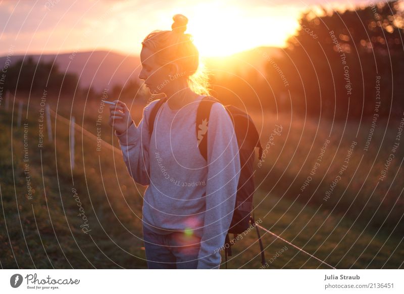 Young woman standing on a pasture in the mountains smoking a cigarette at sunset Woman Adults 1 Human being 18 - 30 years Youth (Young adults) Sunrise Sunset