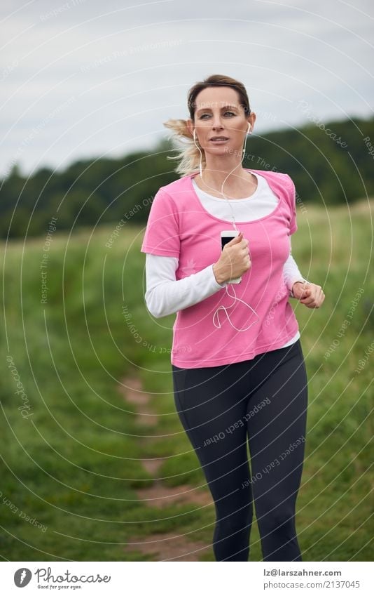 Concentrated woman running through field Lifestyle Face Summer Music Sports Jogging PDA Woman Adults 1 Human being 30 - 45 years Nature Autumn Blonde Fitness