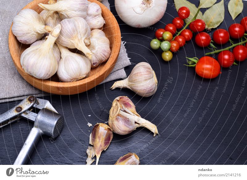 Fresh garlic in a wooden bowl Vegetable Herbs and spices Nutrition Bowl Wood Metal Gray Red Black White Garlic seasoning food Tomato Cherry husk napkin Top
