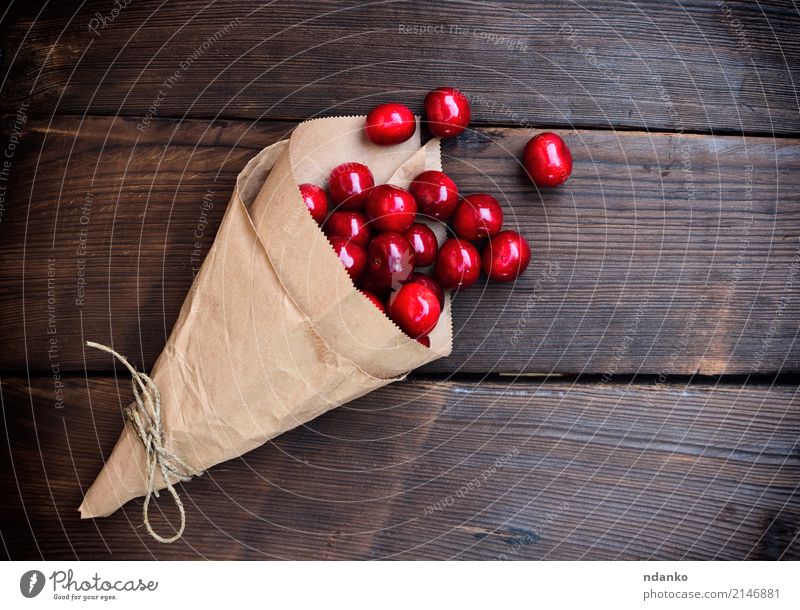 Ripe red cherry in a paper bag Fruit Dessert Eating Vegetarian diet Juice Summer Garden Table Nature Paper Wood Fresh Natural Above Juicy Red background Berries