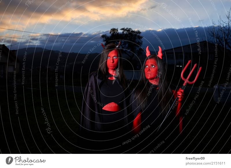 Two woman disguised as devils in the dark Lifestyle Cosmetics Make-up Facial painting Bodypainting Leisure and hobbies Playing Disguised Carnival