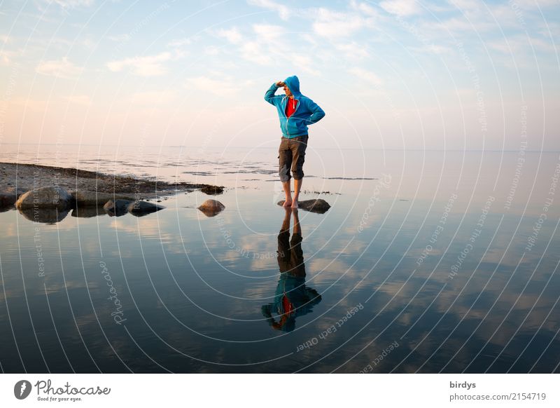Man with blue hooded jacket stands on a stone in the water of the Baltic Sea and looks towards the mainland coast Water Calm Adults Observe 1 Barefoot