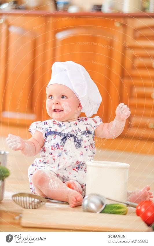 A cute little girl in chef's hat sitting on the kitchen floor soiled with flour, playing with food, making a mess and having fun Lifestyle Joy Human being Child