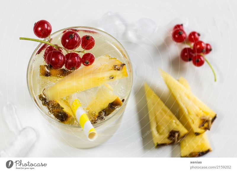 Cool fresh drink with pineapple, red currants, ice cubes and drinking straw in yellow Beverage Pineapple Redcurrant Ice cube Vitamin Cold drink Organic produce
