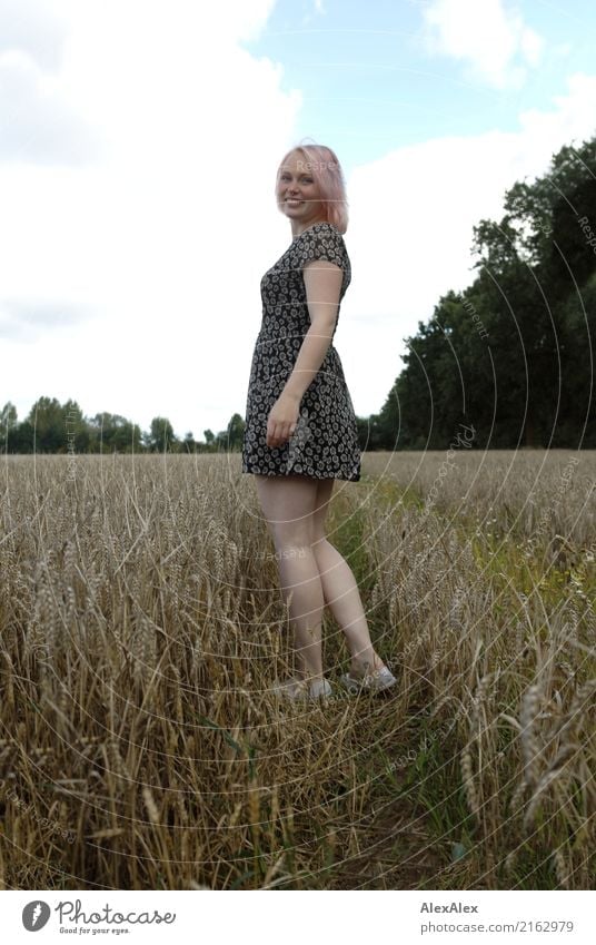 Portrait of a young woman in a summer dress, standing in a field and turning around smiling Grain Joy already Body Contentment Trip Adventure Young woman