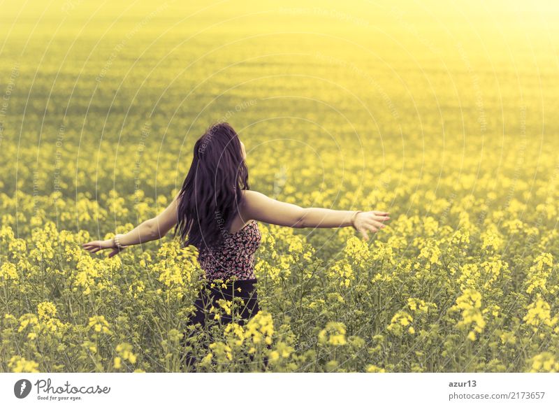 Beautiful young woman in summer on yellow meadow from rape to horizon. Pretty girl with zest for life enjoys the sunshine break and life. Rest and recharge energy from time stress in environment and nature idyll. Outstretched arms.