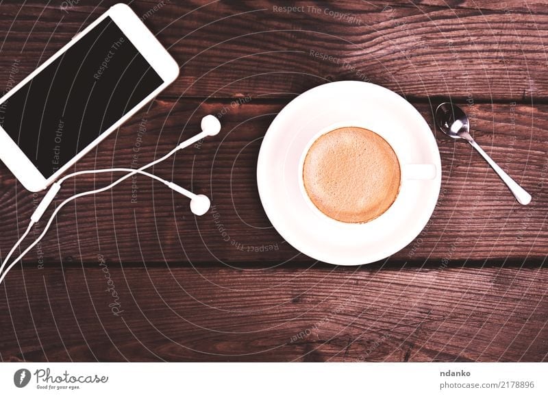 white cup with coffee and foam Breakfast Beverage Coffee Espresso Table Restaurant Telephone PDA Screen Wood Hot Natural Brown Black White Colour cappucino