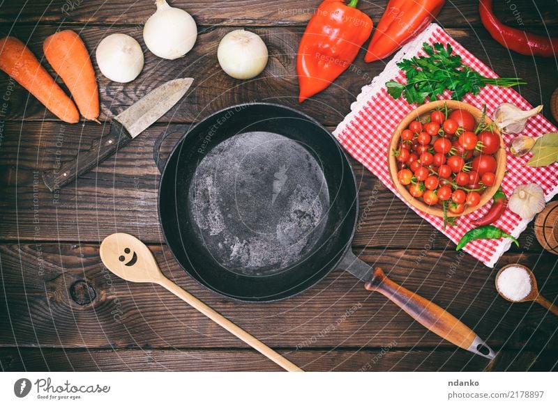 empty black round frying pan Vegetable Nutrition Eating Pan Spoon Kitchen Wood Brown Black Cast iron Tomato Onion salt knife ripe cook Ingredients lettuce