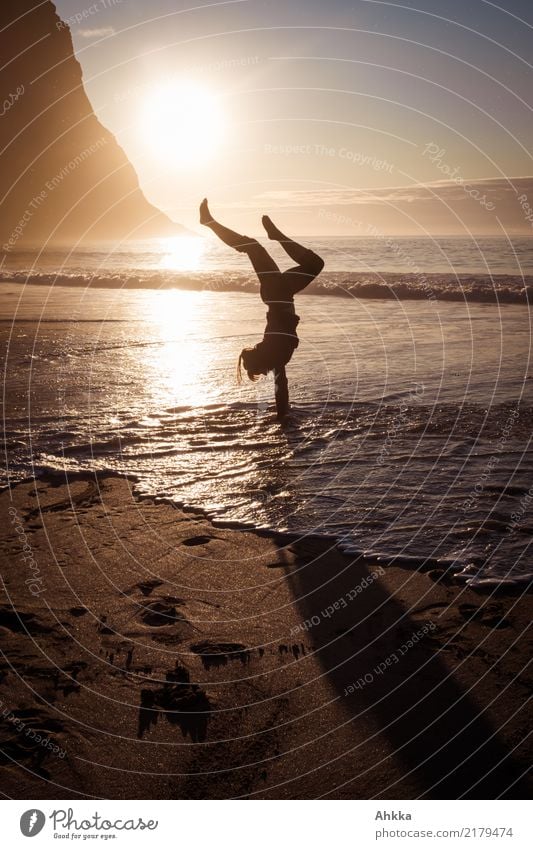 Young woman doing handstand on beach in water in evening back light balance Handstand upside down Figure Yoga Water Ocean Healthy Silhouette equilibrium