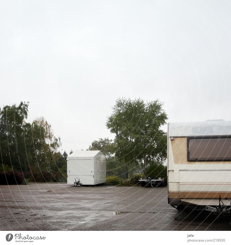 parking space Sky Bad weather Plant Tree Bushes Places Parking lot Means of transport Site trailer Trailer Gloomy Gray Green White Wet Colour photo
