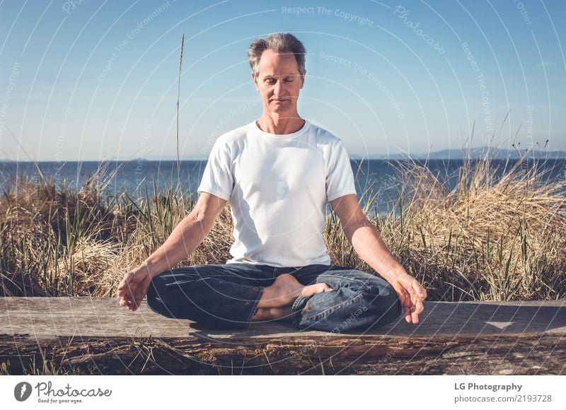 Man sitting in a relaxed yoga pose at the beach. Relaxation Meditation Sun Yoga Adults Old Sit Natural Power Serene 50-60 years Action color image