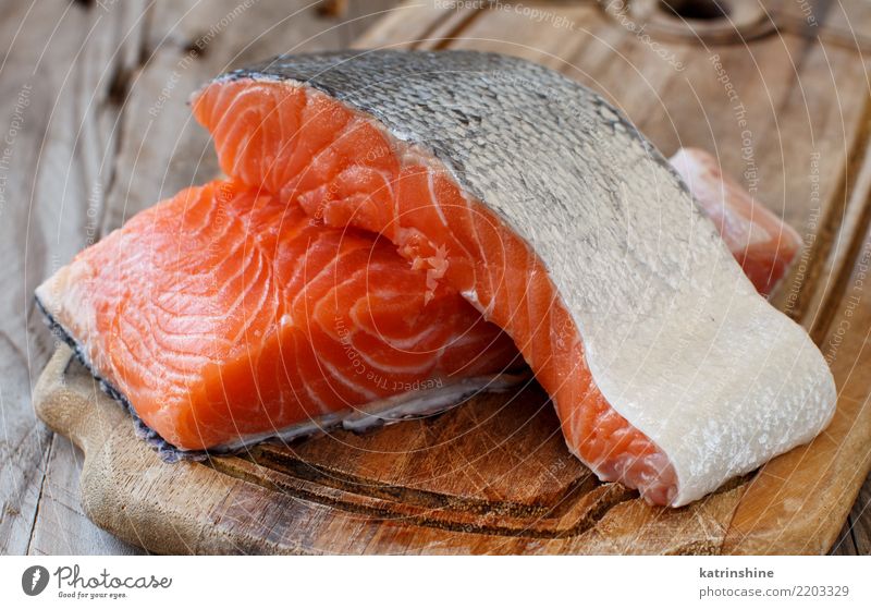 Fresh raw salmon on a wooden cutting board Fish Seafood Nutrition Eating Dinner Diet Table Red background cooking fillet healthy Ingredients Meal Portion
