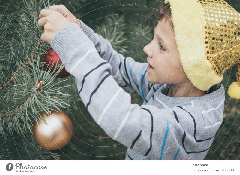 Happy young little boy decorating Christmas tree Lifestyle Joy Beautiful Face Playing Winter Decoration Feasts & Celebrations Christmas & Advent Child