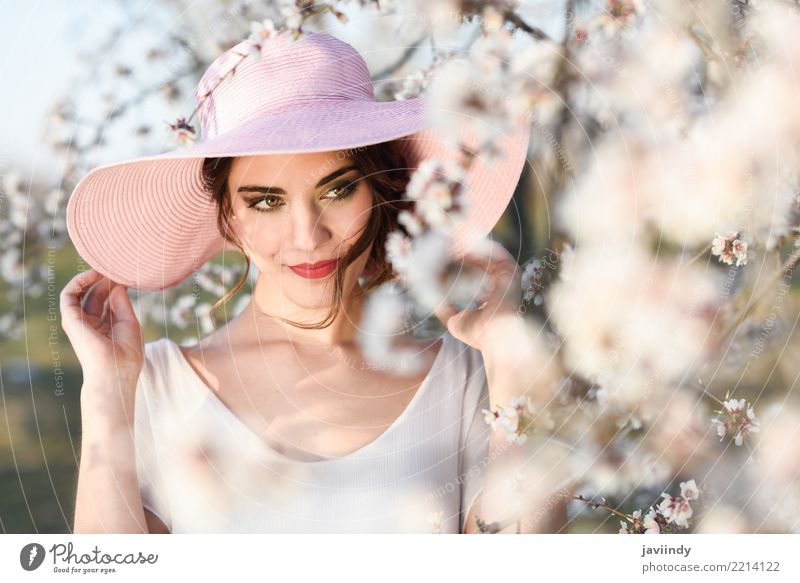Woman in the flowered field in the spring time Style Happy Beautiful Face Human being Adults Nature Tree Flower Blossom Park Fashion Dress Hat Brunette Pink