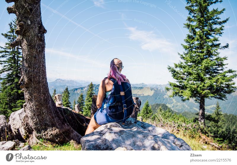 Young woman takes a break in the Alps Hiking Nature Landscape Summer Beautiful weather Tree Bushes Rock Mountain Sunglasses Backpack Blonde Cow Think To enjoy