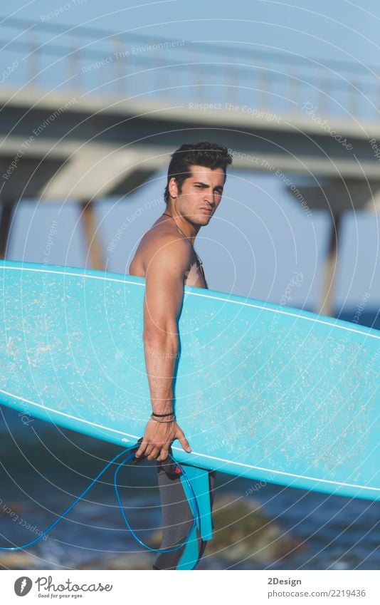 Young attractive surfer holding his surfboard at the beach Lifestyle Joy Vacation & Travel Summer Beach Ocean Waves Sports Man Adults Youth (Young adults) Sky