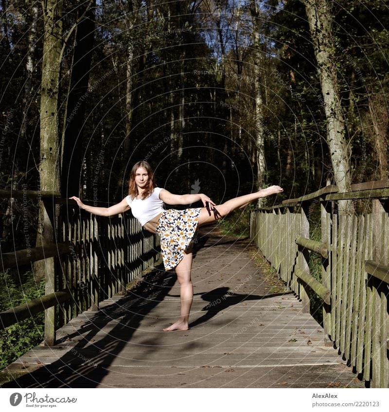 Young very athletic woman standing barefoot on a wooden bridge in the woods doing a dance pose barefoot and belly Joy pretty Athletic Fitness Life Gymnastics