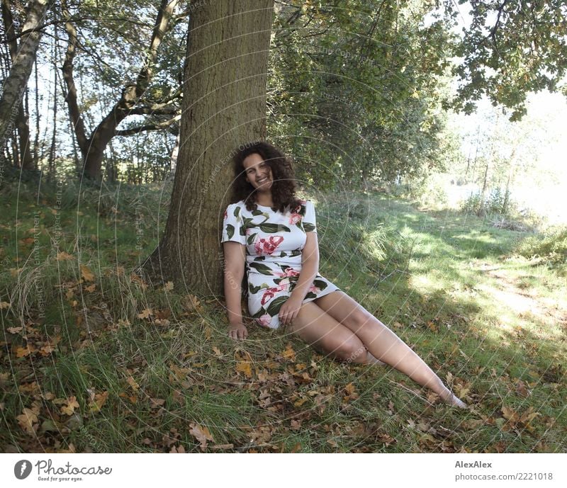 Full body image of tall beautiful woman with long dark curly hair in nature sitting barefoot under tree Joy pretty Life Harmonious Trip Young woman