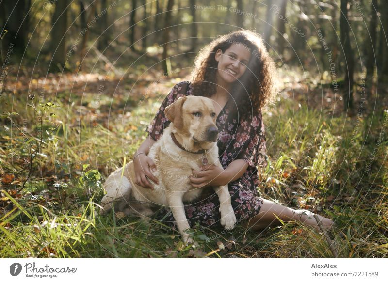 Portrait of young blond Labrador with young tall beautiful woman with long dark curls in back light forest Joy Life Contentment Young woman Youth (Young adults)