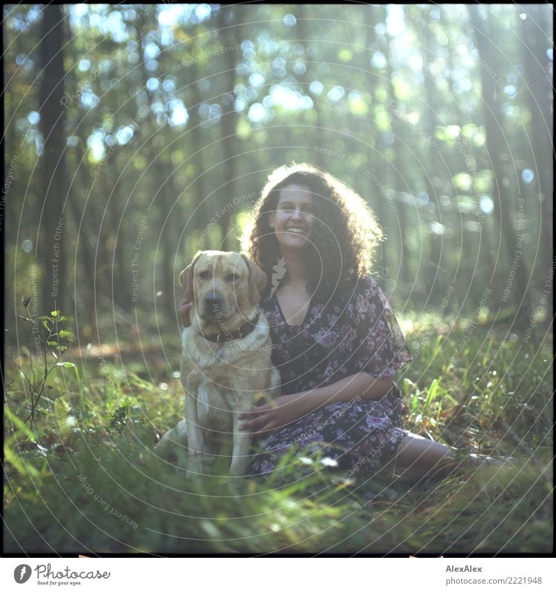 analog medium format photo: young blond Labrador in forest with tall dark haired woman with wild curls smiling at camera Joy pretty Life Harmonious Young woman