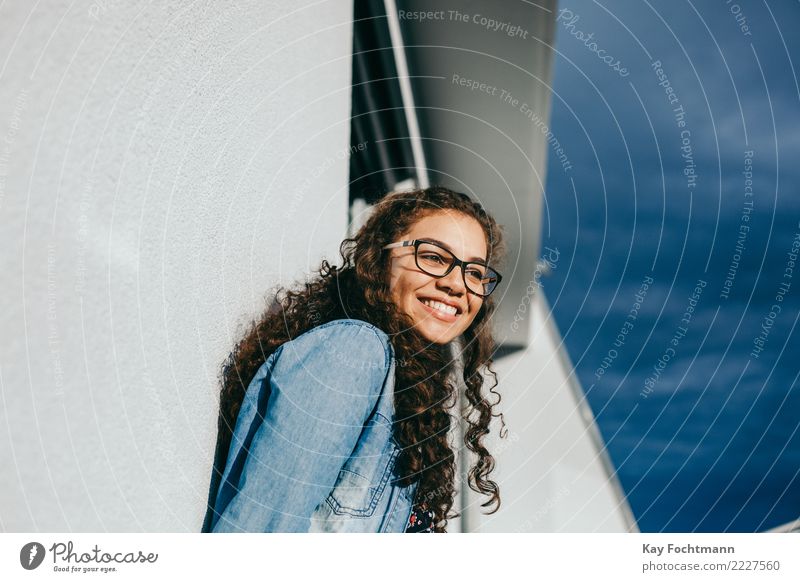 Smiling woman with curly hair and glasses leaning against the house wall Lifestyle Joy Happy Healthy Wellness Well-being Contentment Feminine Young woman