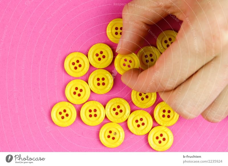 Yellow buttons Man Adults Hand Fingers To hold on Pink Select Take Buttons majority Selection Many Colour photo Interior shot Close-up Copy Space left Downward