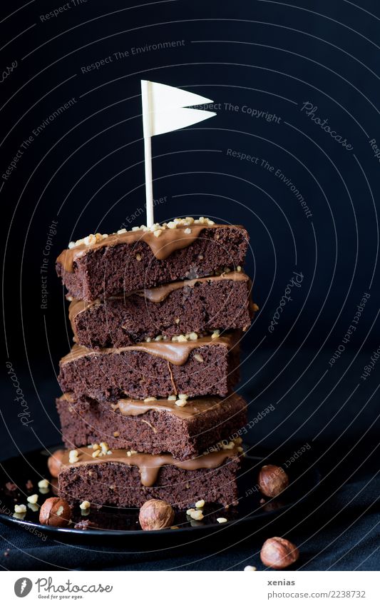 piled up pieces of chocolate cake with hazelnut cream and white flag in front of dark background Food Cake Chocolate brownie Chocolate cake Hazelnut Cream