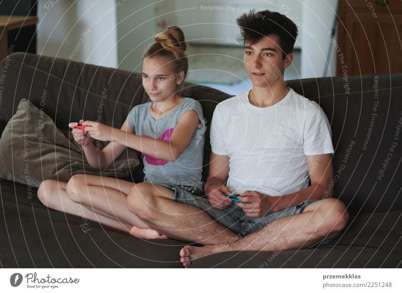 Concentrated young boy and girl playing video games sitting on sofa at home Lifestyle Joy Leisure and hobbies Playing Living or residing Sofa Child Technology