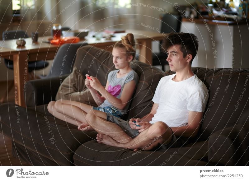 Boy and girl playing video games sitting on sofa at home Lifestyle Joy Leisure and hobbies Playing Sofa Child Technology Girl Boy (child) Young woman