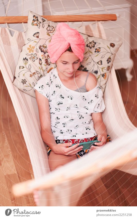 Teenage girl with towel on head using mobile phone sitting in hammock at home Lifestyle Shopping Leisure and hobbies Child Telephone Cellphone PDA Technology