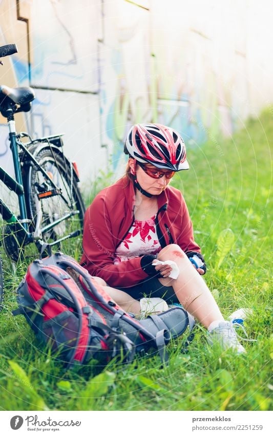 Woman dressing the wound on her knee with medicine in spray Lifestyle Vacation & Travel Summer Sports Cycling Human being Adults Grass Pain accident Action