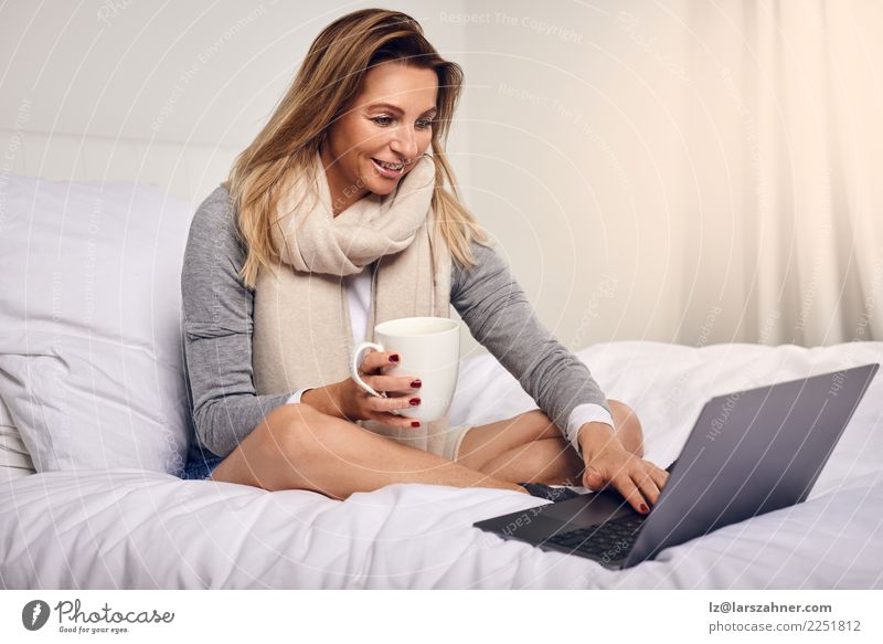 Attractive woman sitting on her bed with coffee Coffee Tea Lifestyle Shopping Happy Contentment Bedroom Work and employment Computer Notebook Technology