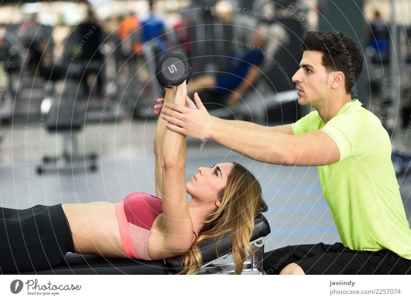 Personal trainer helping a young woman lift weights Lifestyle Body Sports Human being Masculine Feminine Young woman Youth (Young adults) Young man Woman Adults