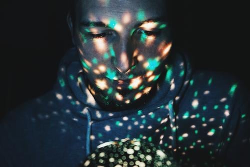 Young man illuminated by fairy lights Lifestyle Design Exotic Human being Masculine Youth (Young adults) 1 30 - 45 years Adults Art Sweater Designer stubble