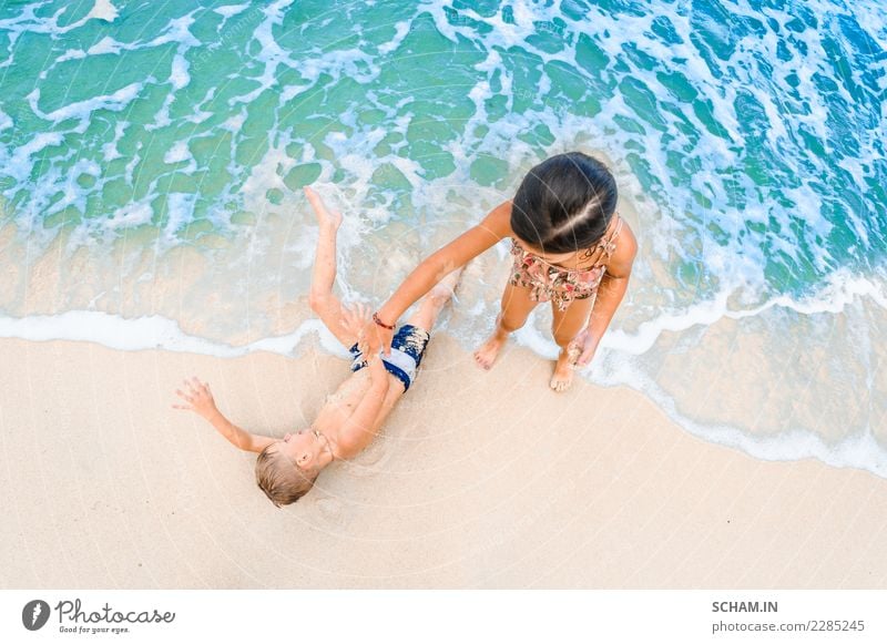 Cute boy and girl having fun on the sunny tropical beach. Lying on sand, wonderful waves around them. View from above Lifestyle Joy Beautiful Freedom Summer